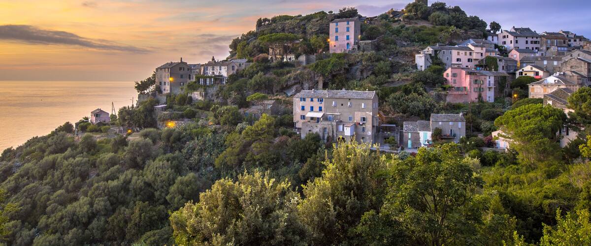 A coastal village with buildings on a hillside, overlooking the sea.