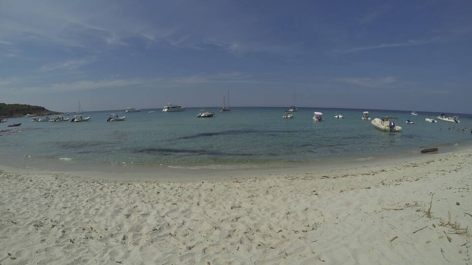 A sandy beach with boats anchored in the water.