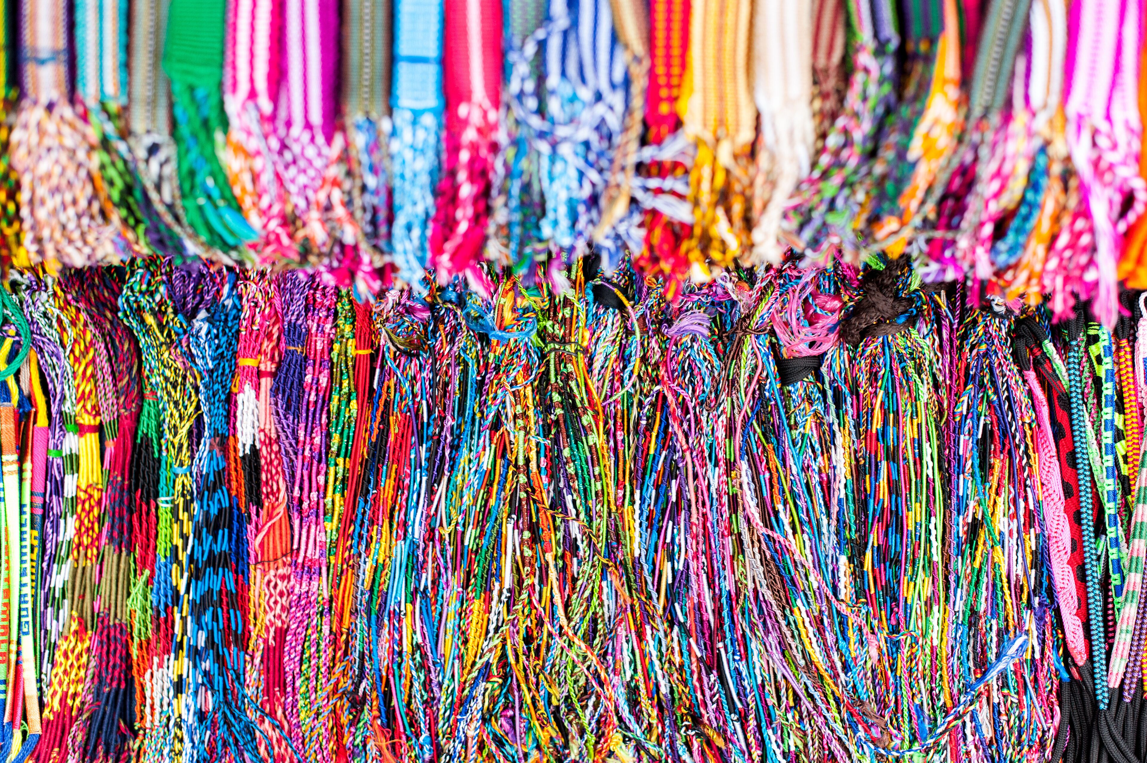 Uma variedade de pulseiras e colares coloridos, feitos com tecido.