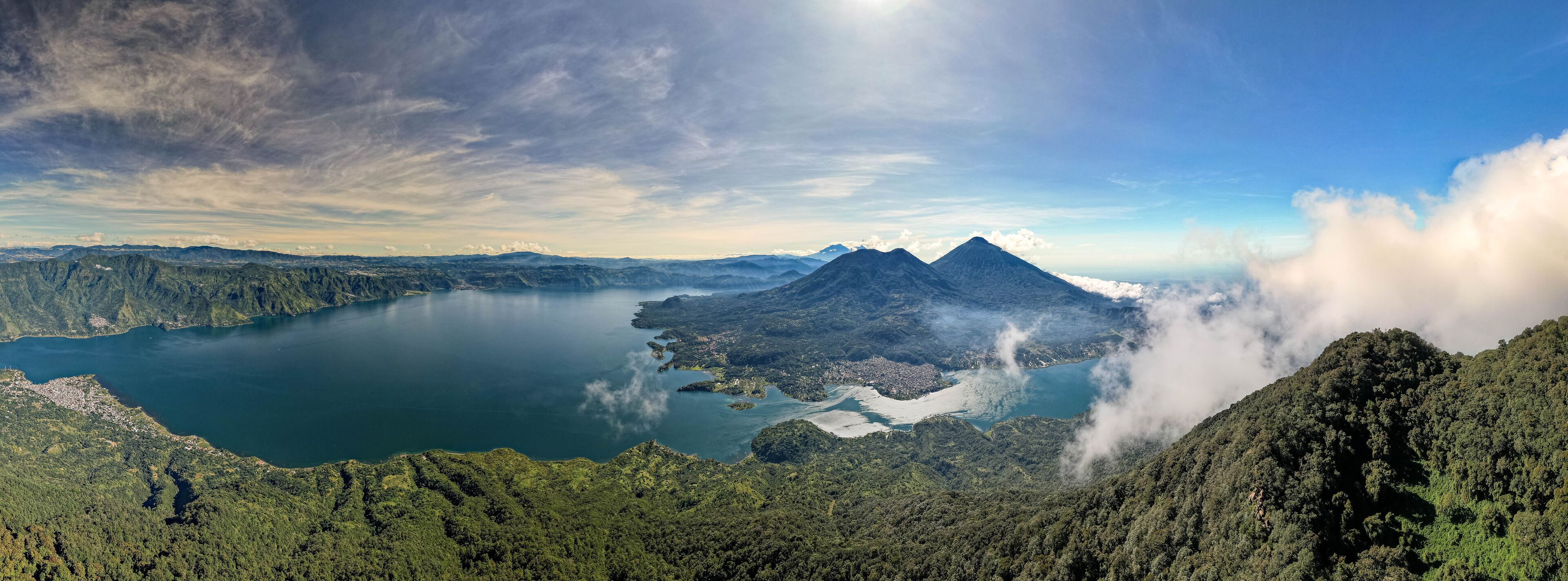 A mountainous landscape with a lake, a volcano, and a forested area.