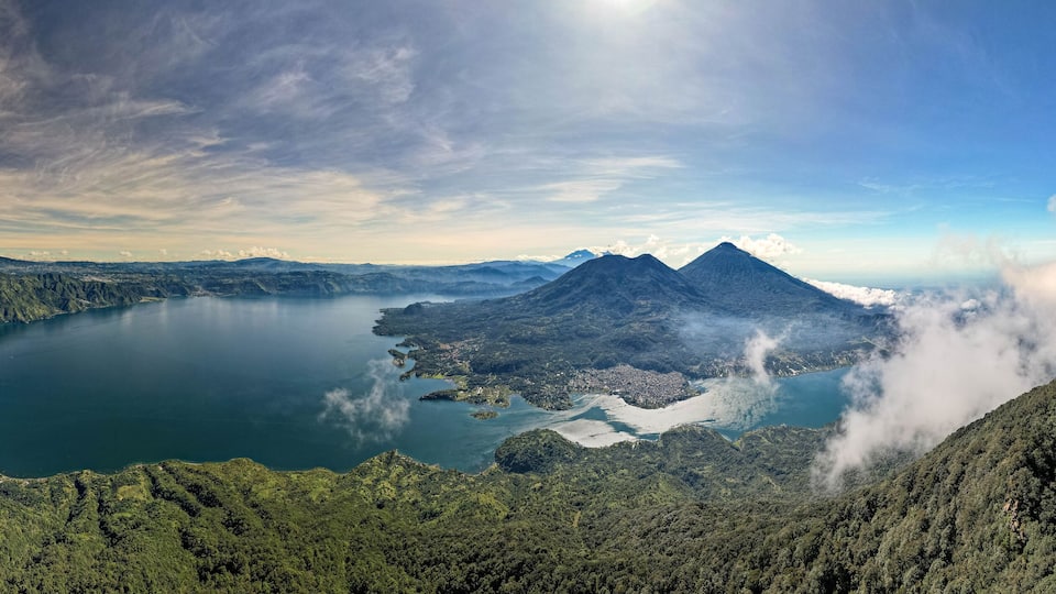 A mountainous landscape with a lake, a volcano, and a forested area.