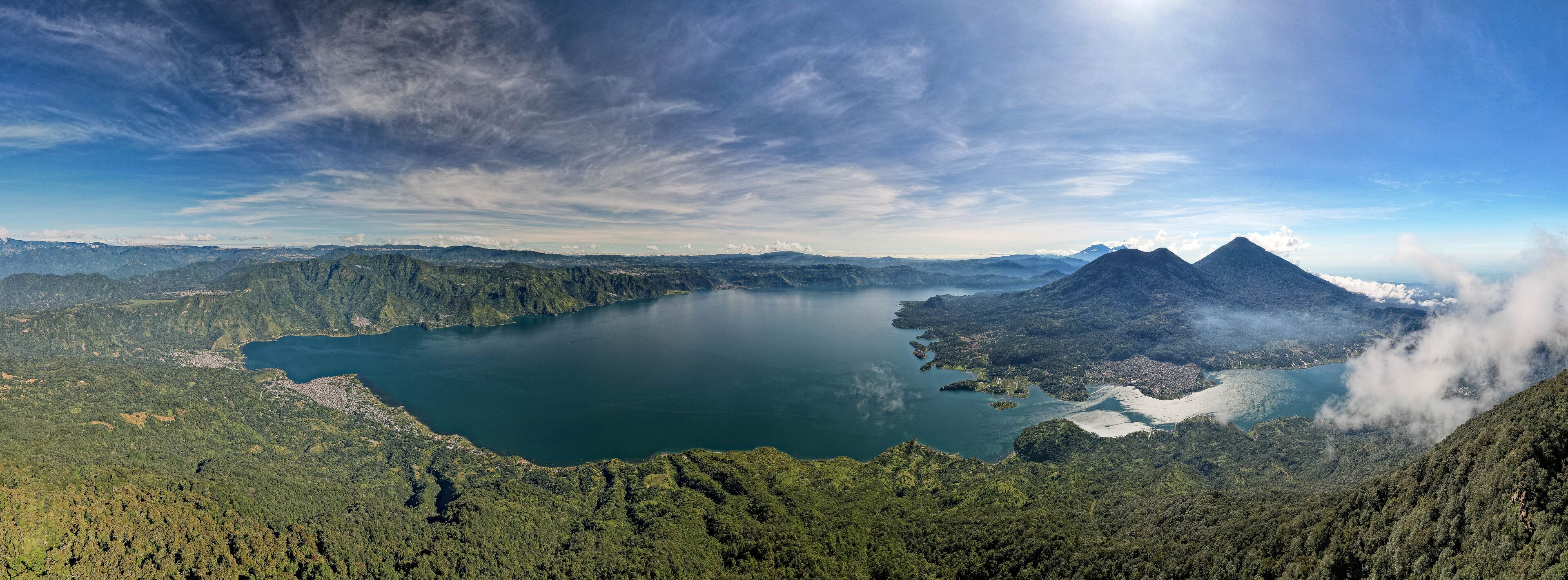 Vista panorâmica de um lago rodeado por montanhas e floresta densa.