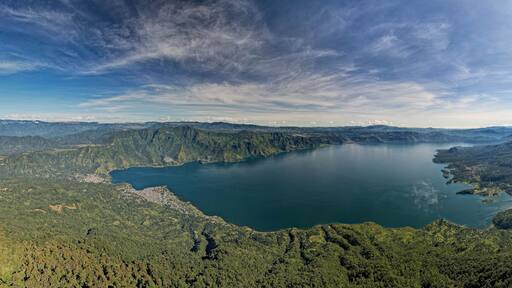 Vista panorámica de un lago rodeado de montañas y un bosque denso.