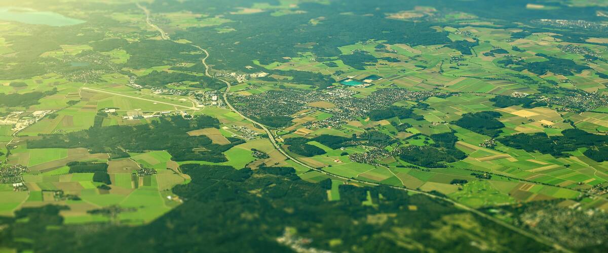 An aerial view of a rural landscape with fields, a winding road, and scattered buildings.