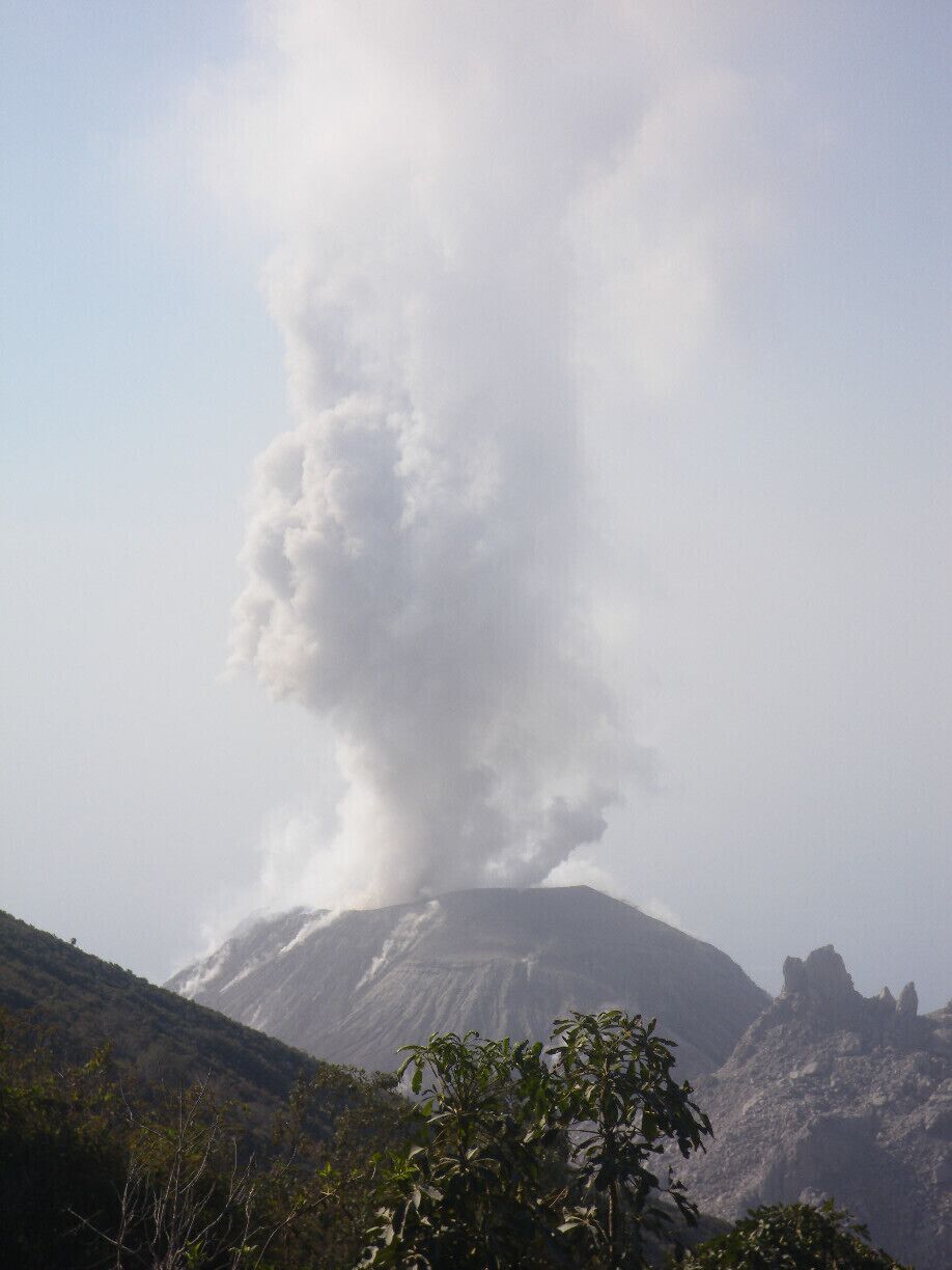 Un volcán con una columna de humo elevándose hacia el cielo.