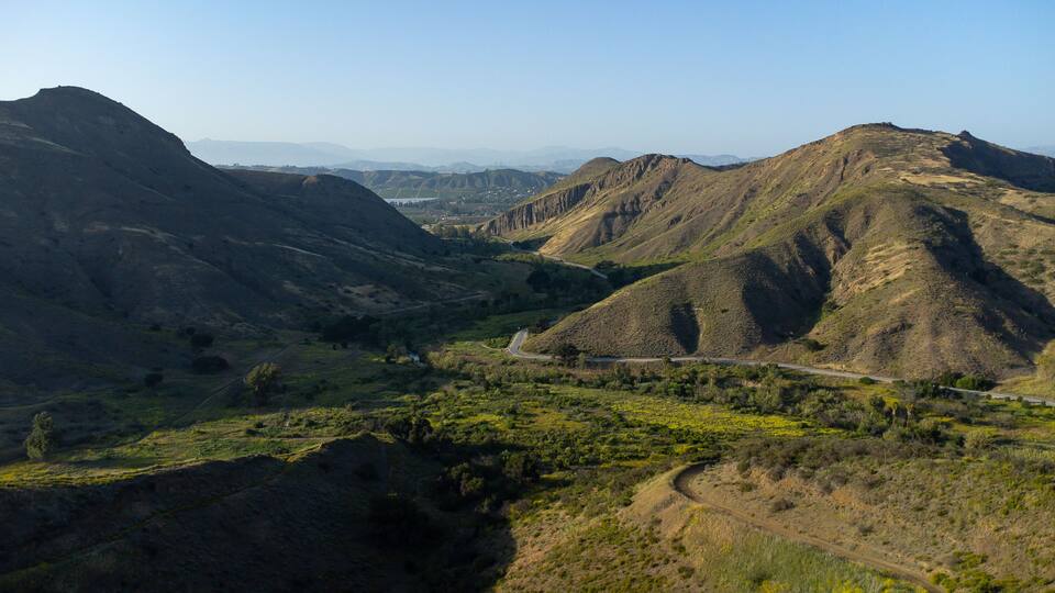 A mountainous landscape with a winding road through a valley.