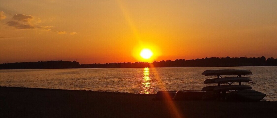 A sunset over a body of water with a bench in the foreground.