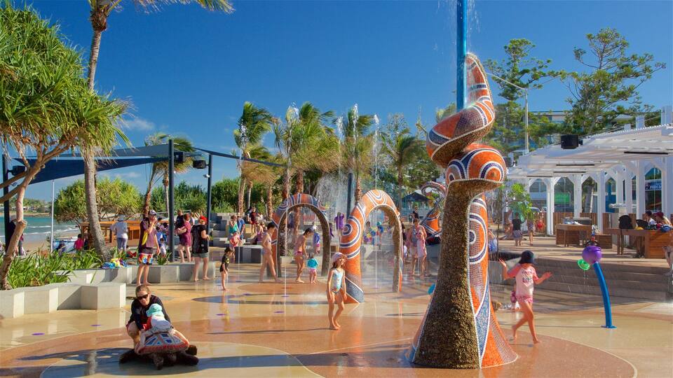 A water park with a large, colorful water fountain and palm trees.