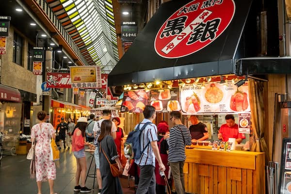 Kuromon Ichiba Market showing interior views and shopping as well as a small group of people