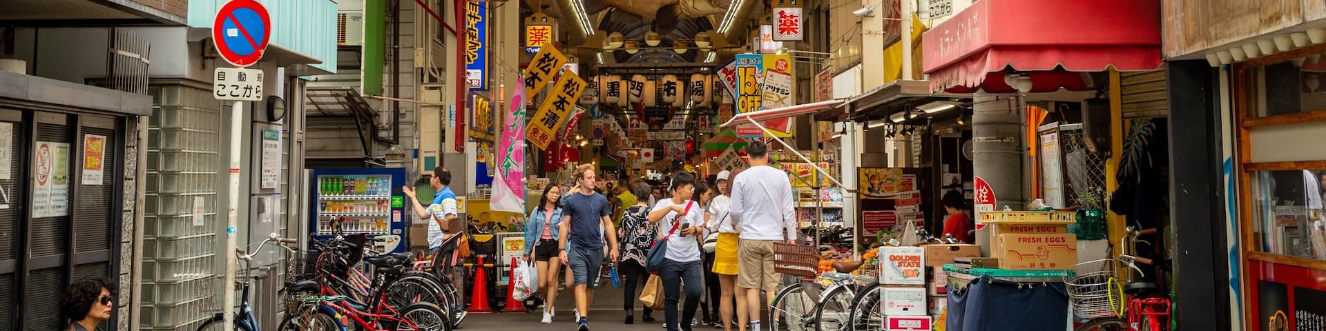 A busy street with a yellow sign reading "Black Market" and various shops and people.