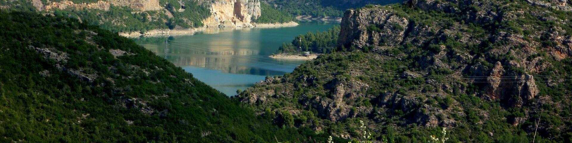 A mountainous landscape with a prominent cliff and a lake.