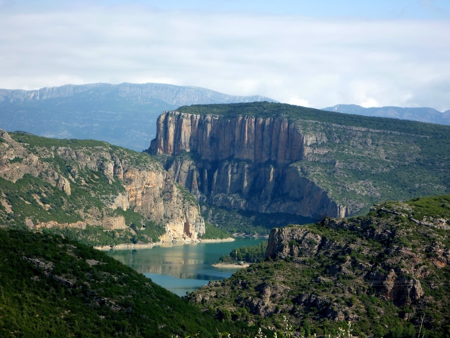 Un paisaje montañoso con un acantilado destacado y un lago.