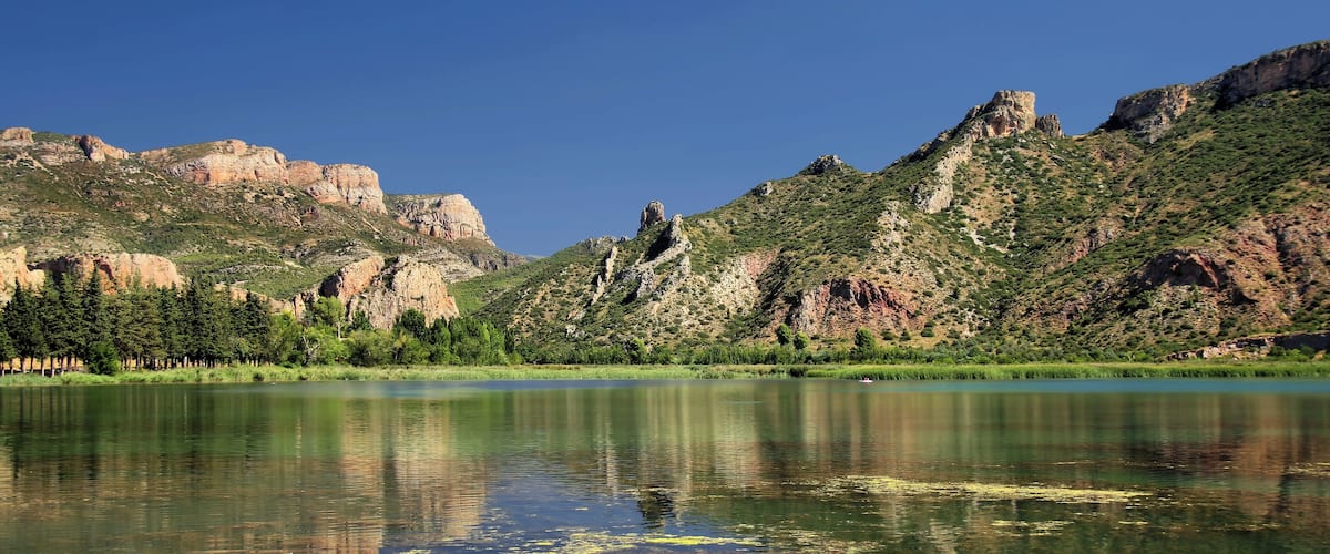 A calm lake reflecting mountains and trees.