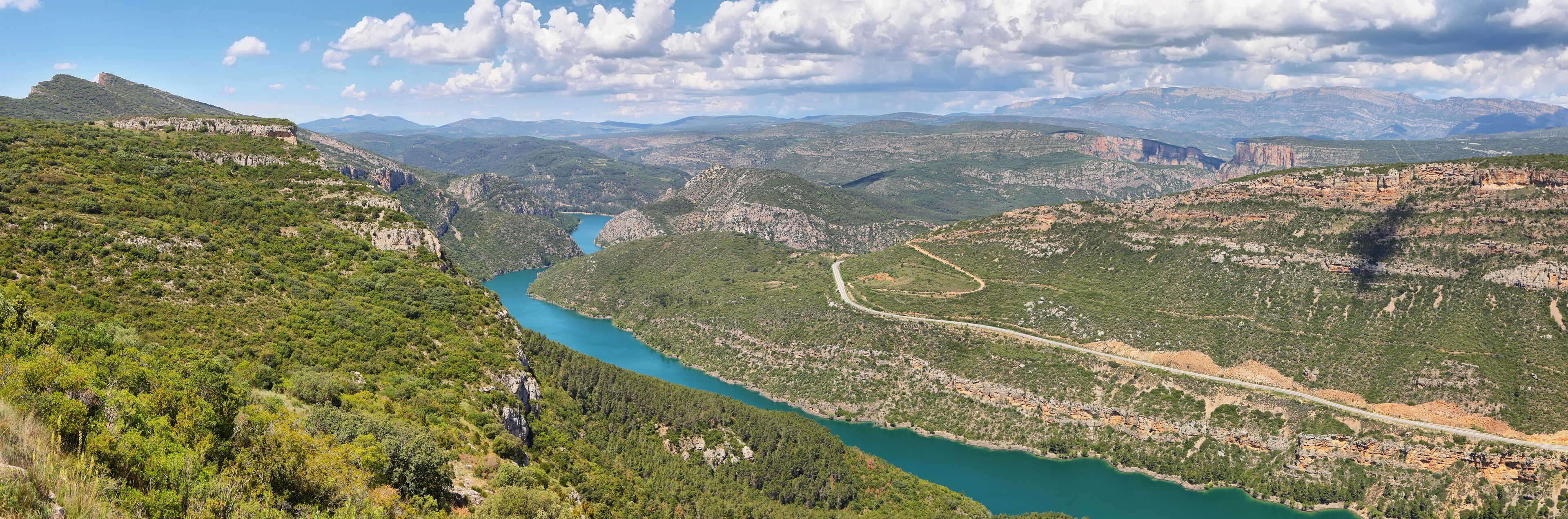 A mountainous landscape with a winding river, dense greenery, and distant mountains.
