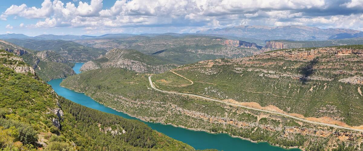 A mountainous landscape with a winding river, dense greenery, and distant mountains.