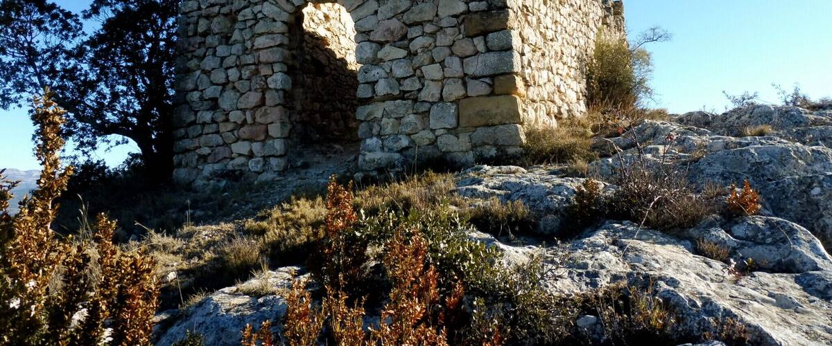 A stone tower with a central arched window, surrounded by rocky terrain and sparse vegetation.