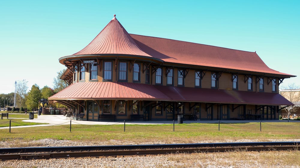 A historic train station with a distinctive red roof and multiple windows.