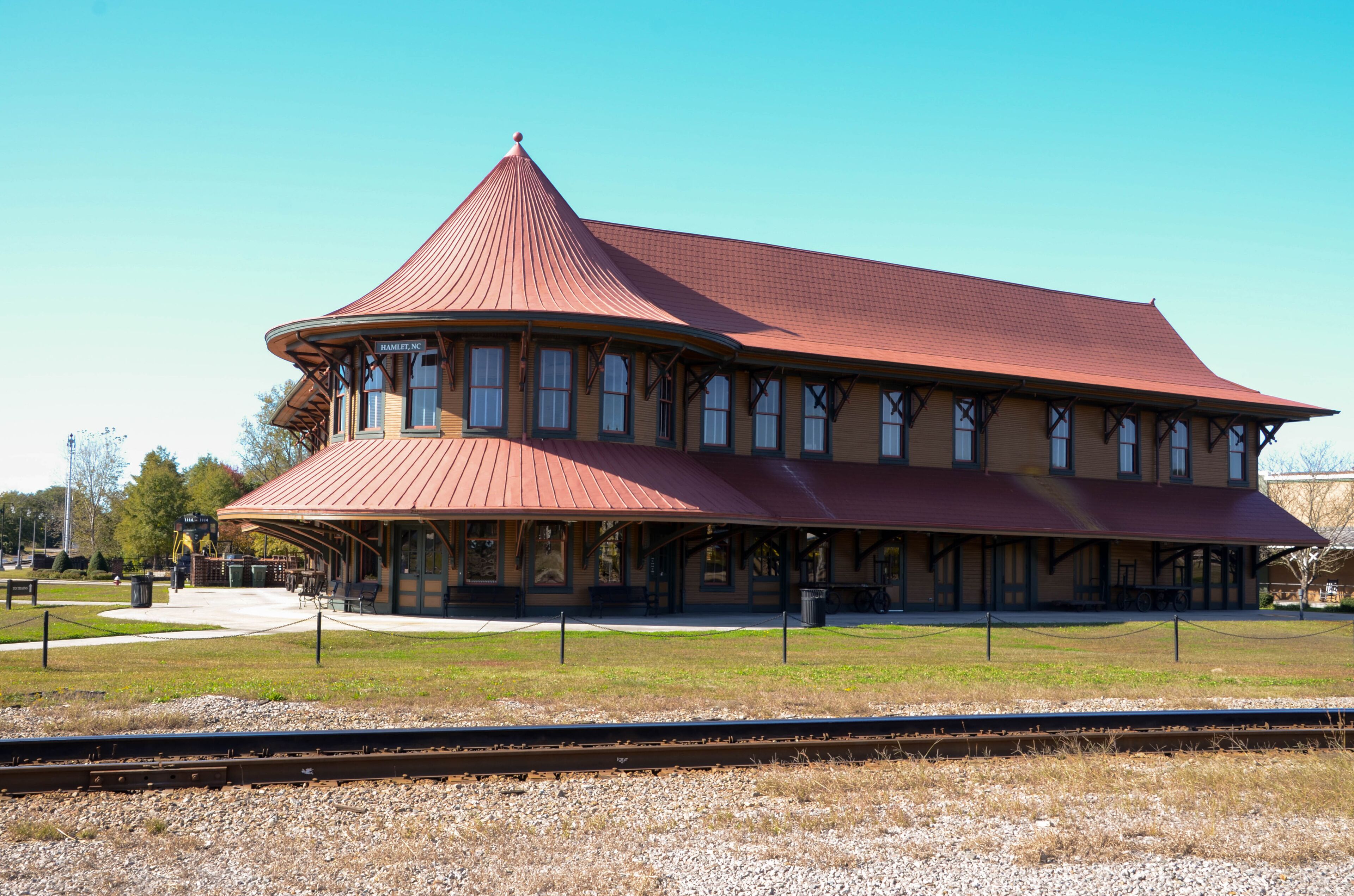 A historic train station with a distinctive red roof and multiple windows.