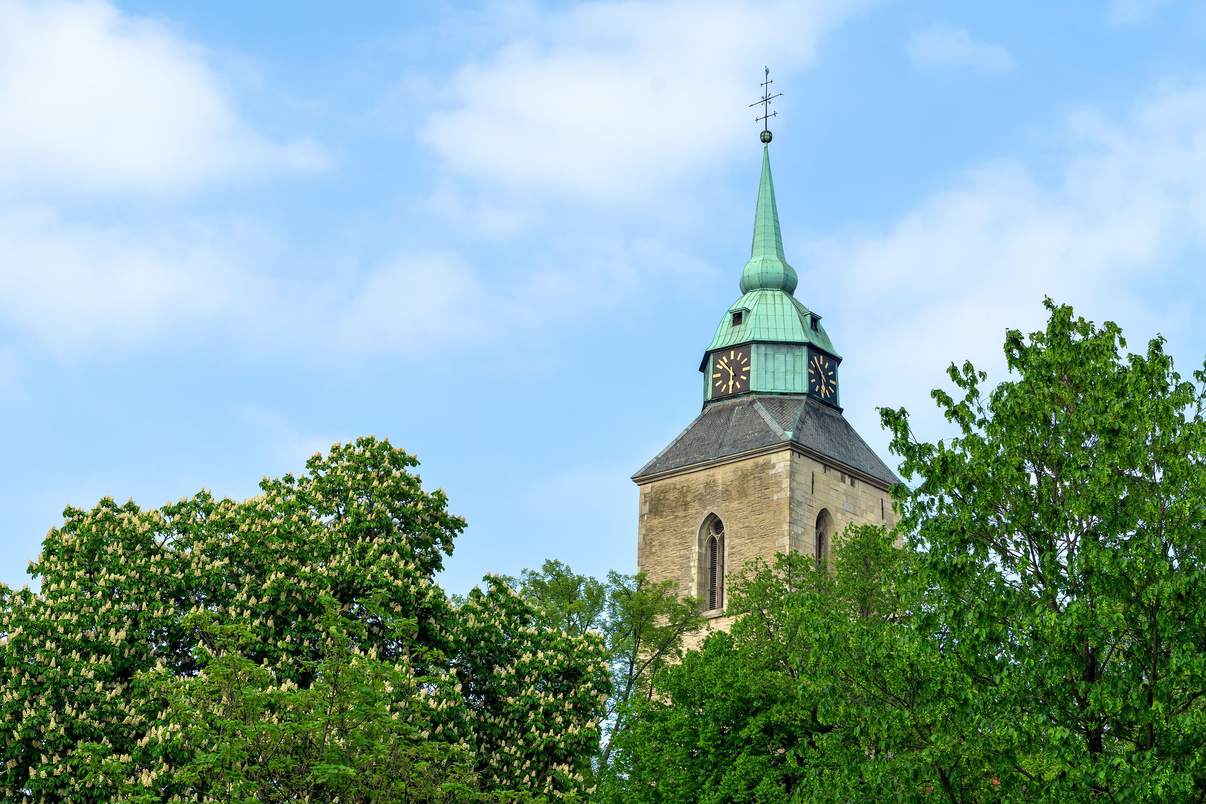A church with a green spire and a clock tower.