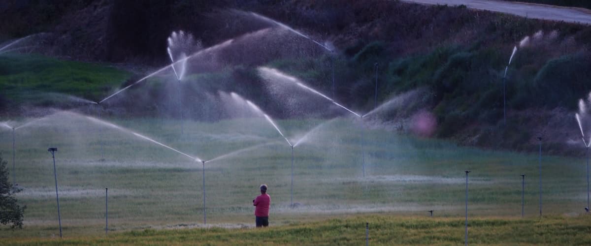 A person in a field with multiple irrigation systems.