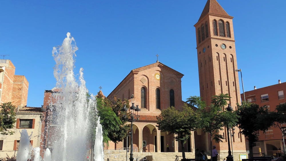 A historic church with a tall bell tower and a central fountain.