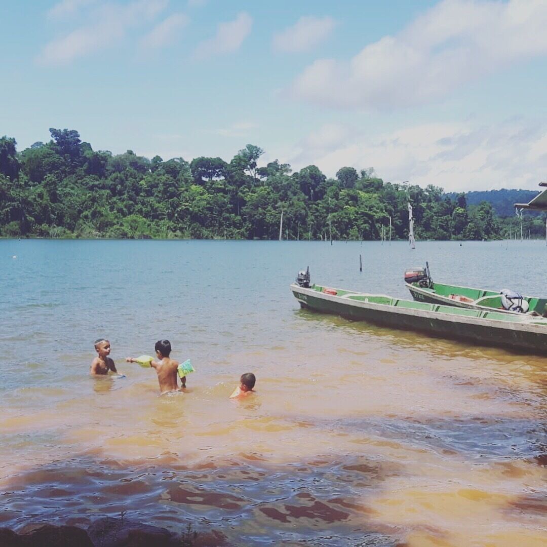 A lake with boats and people swimming.