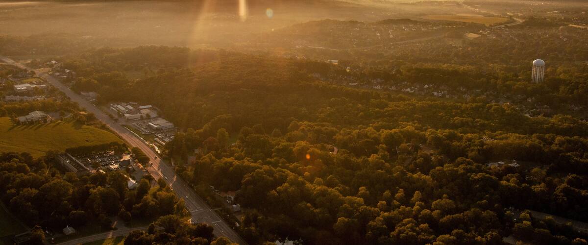 A sunrise over a valley with a water tower, roads, and scattered buildings.