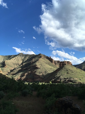 A mountainous landscape with a prominent rock formation and sparse vegetation.