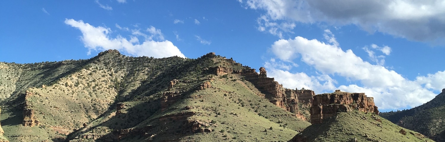 Un paisaje montañoso con una destacada formación rocosa y vegetación escasa.