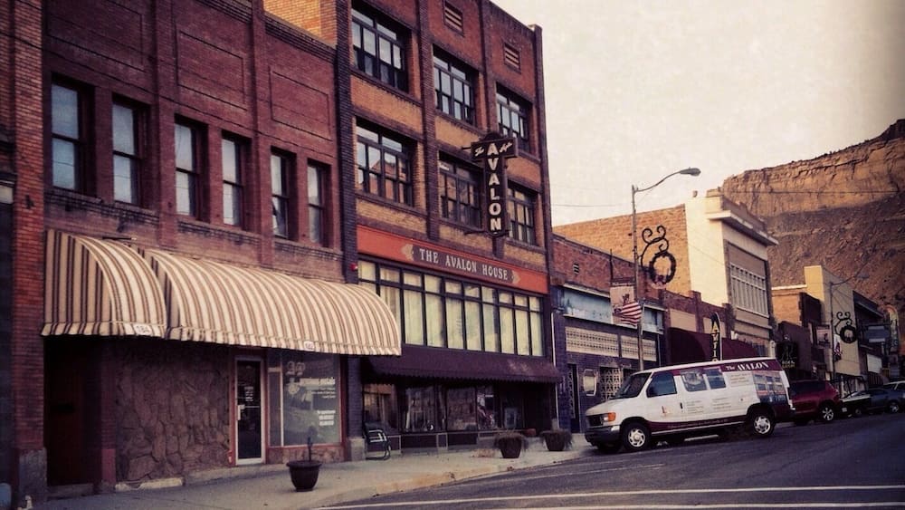 A street with a row of brick buildings, including 'The Avalon House' with a striped awning.