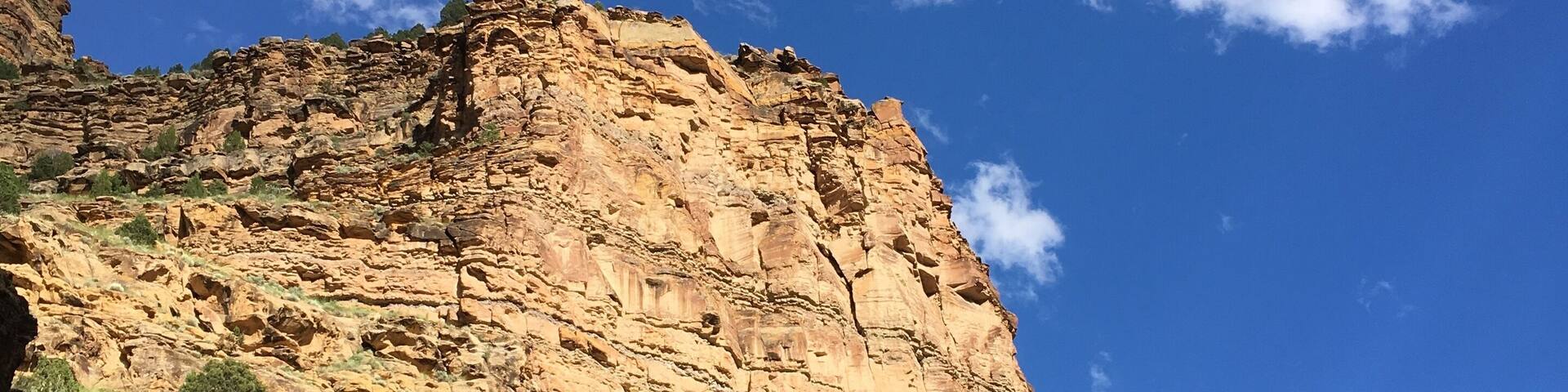 Beautiful mountains with deep blue skies and a few puffy clouds up 9 Mile Canyon, Helper, Utah. warm golden hour light illuminates a mountain cliff in the late afternoon, Nine Mile Canyon, Utah.