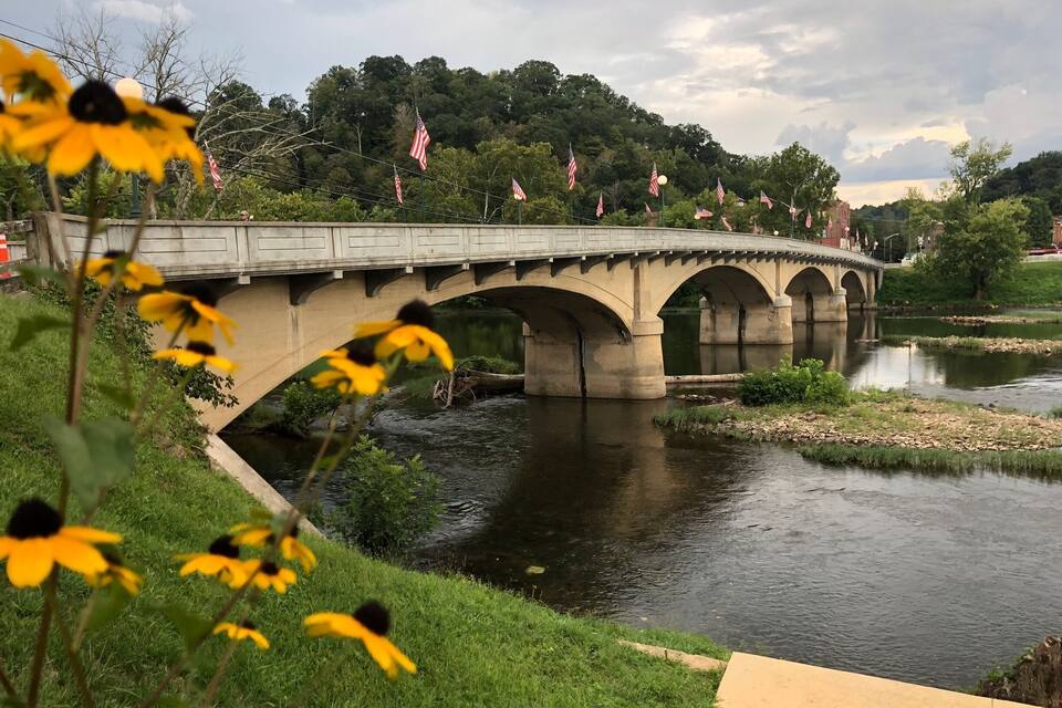 A concrete bridge over a river with American flags.