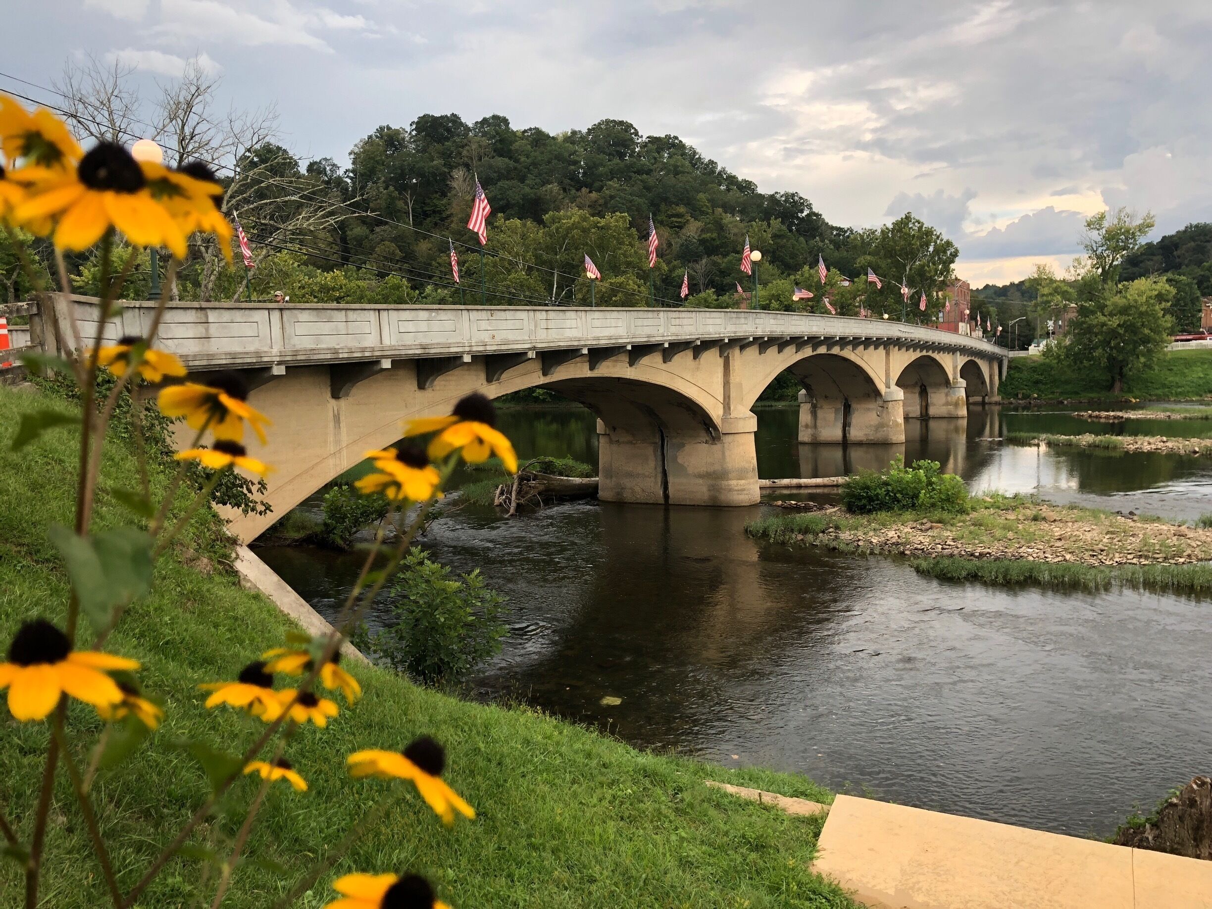A concrete bridge over a river with American flags.