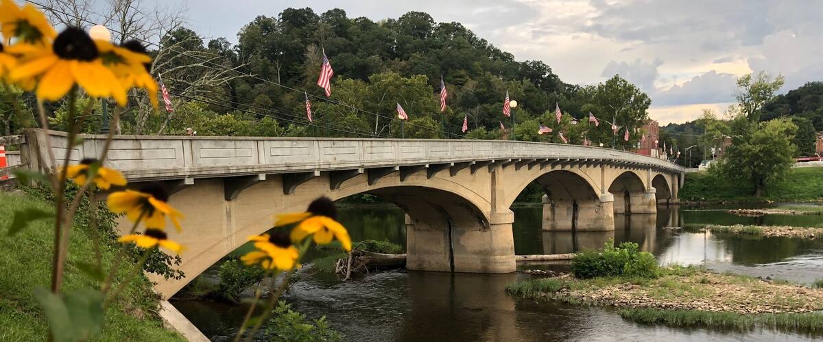A concrete bridge over a river with American flags.