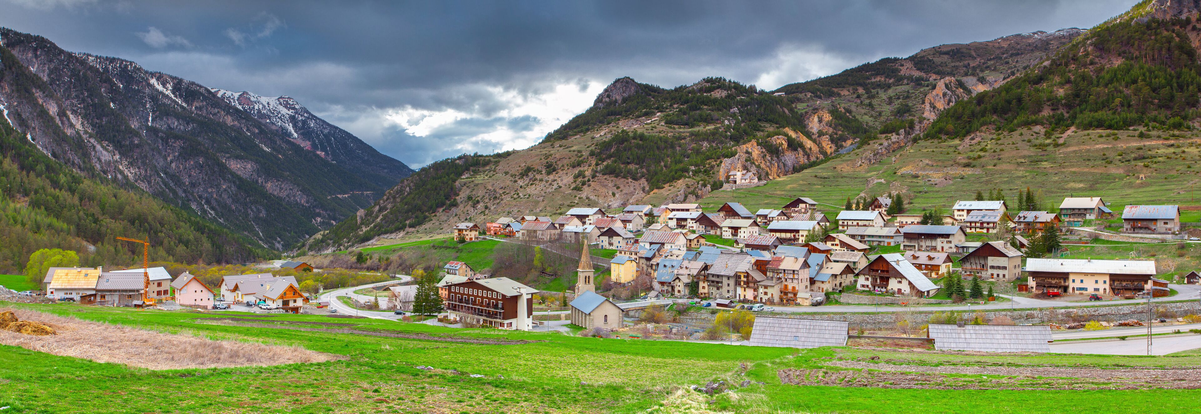 A mountainous village with houses, a church, and a road winding through the valley.
