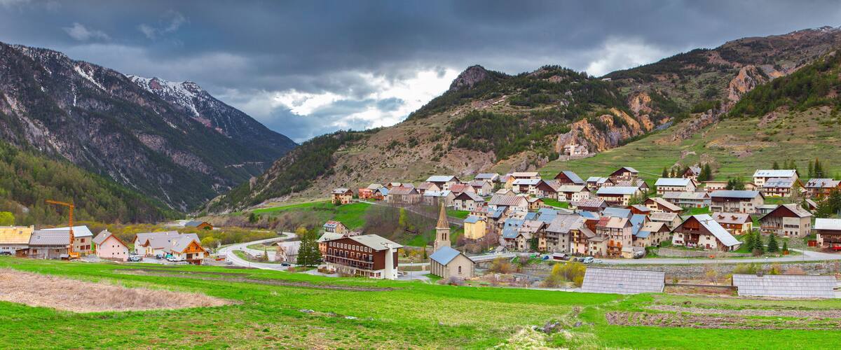 A mountainous village with houses, a church, and a road winding through the valley.