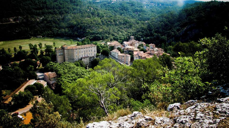 A historic town with a prominent castle-like building surrounded by lush greenery and rolling hills.