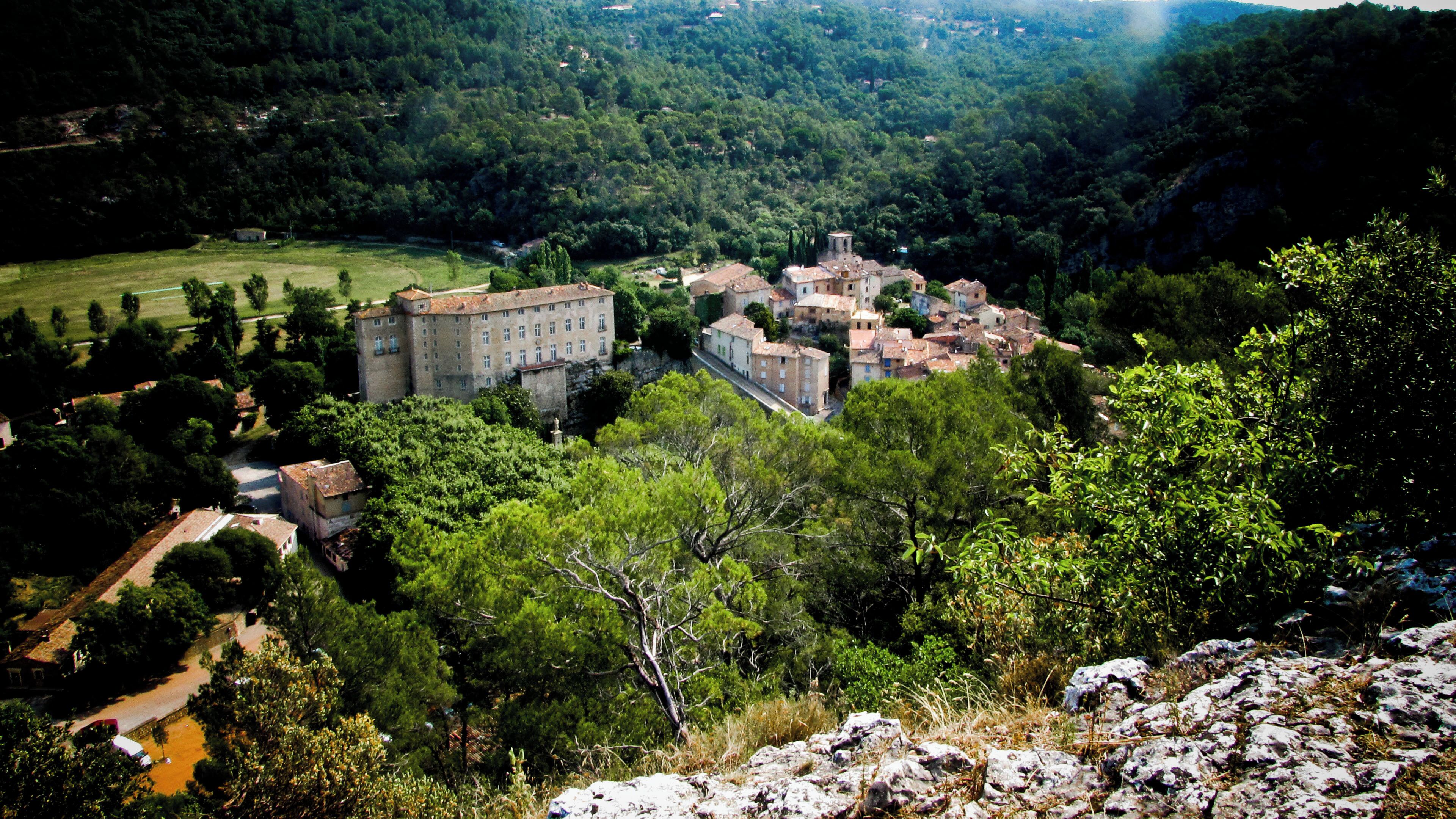 A historic town with a prominent castle-like building surrounded by lush greenery and rolling hills.