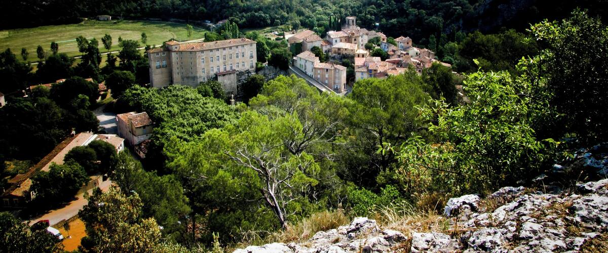 A historic town with a prominent castle-like building surrounded by lush greenery and rolling hills.