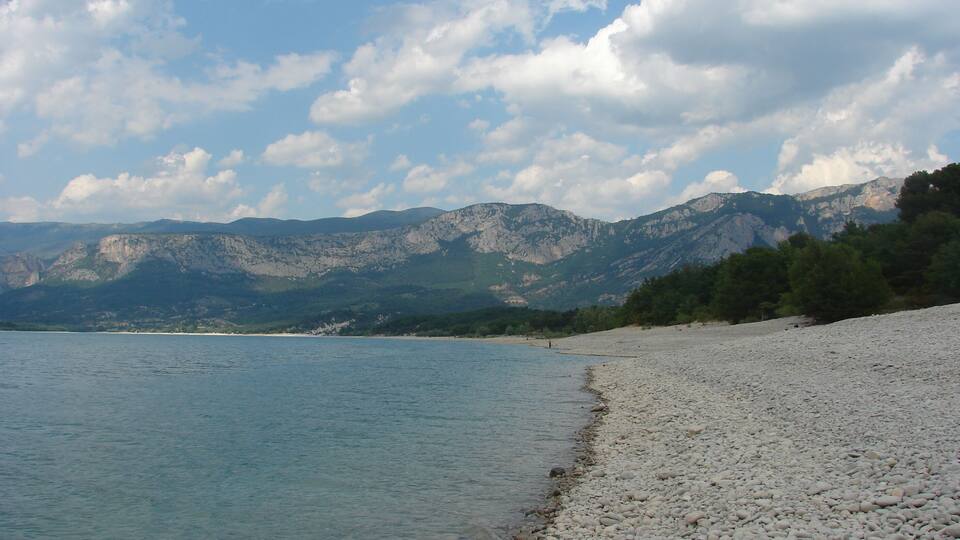 A pebble beach with mountains in the background.