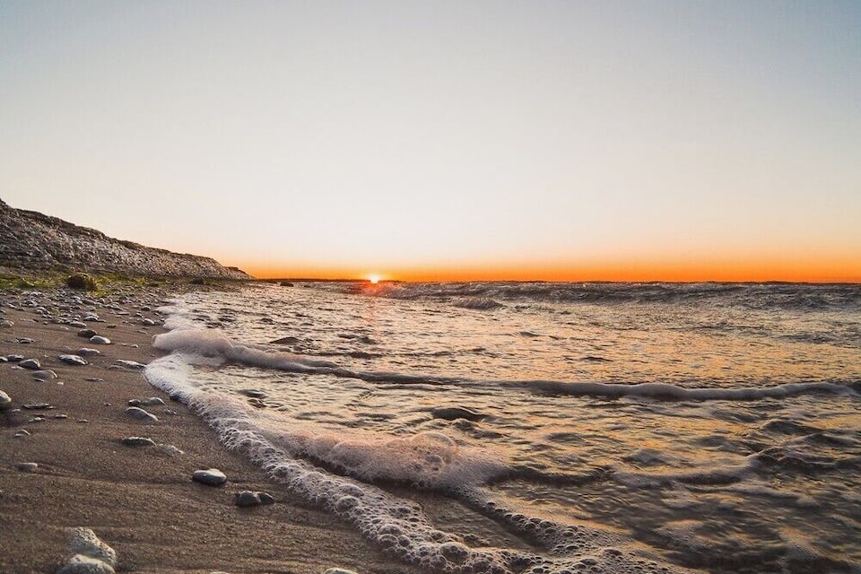 Platja al capvespre amb ones que brollen suaument a la riba.