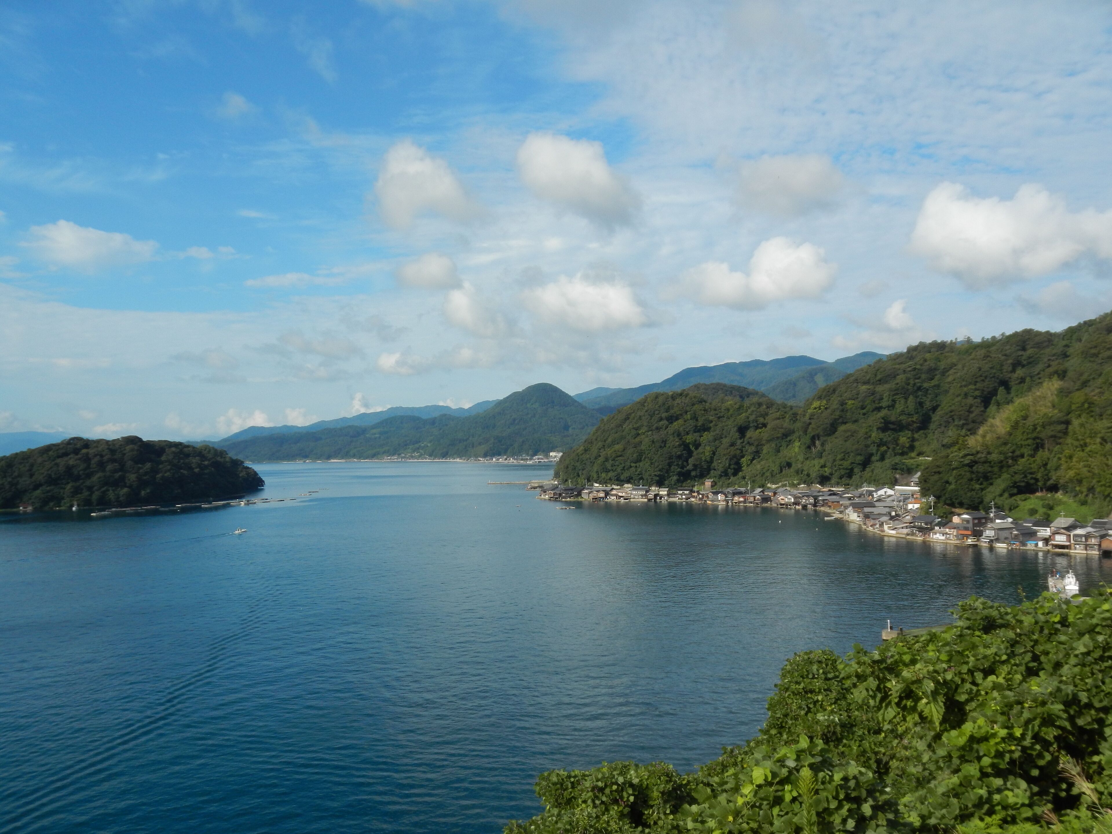 A coastal town with a bay, surrounded by mountains and lush greenery.
