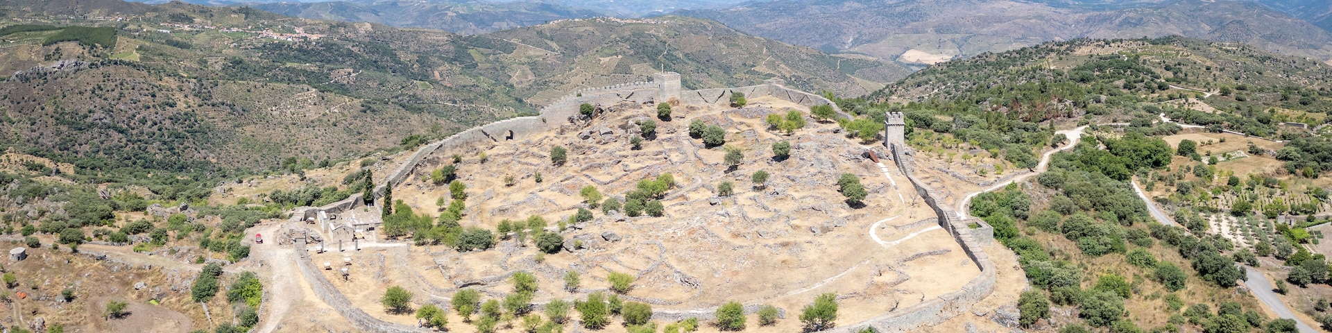 Un antiguo anfiteatro rodeado de terreno montañoso y seco, con vegetación escasa.