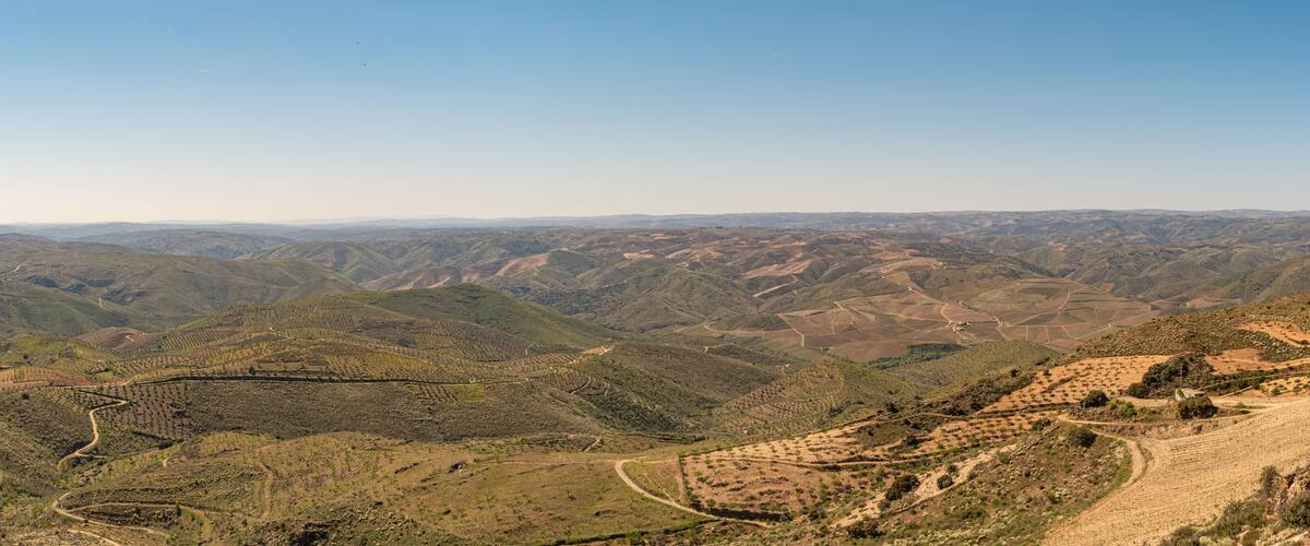 A mountainous landscape with terraced fields and winding roads.