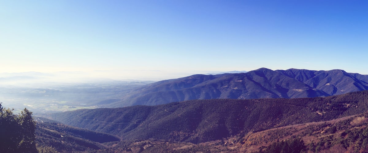 A mountainous landscape with dense forests and a clear sky.