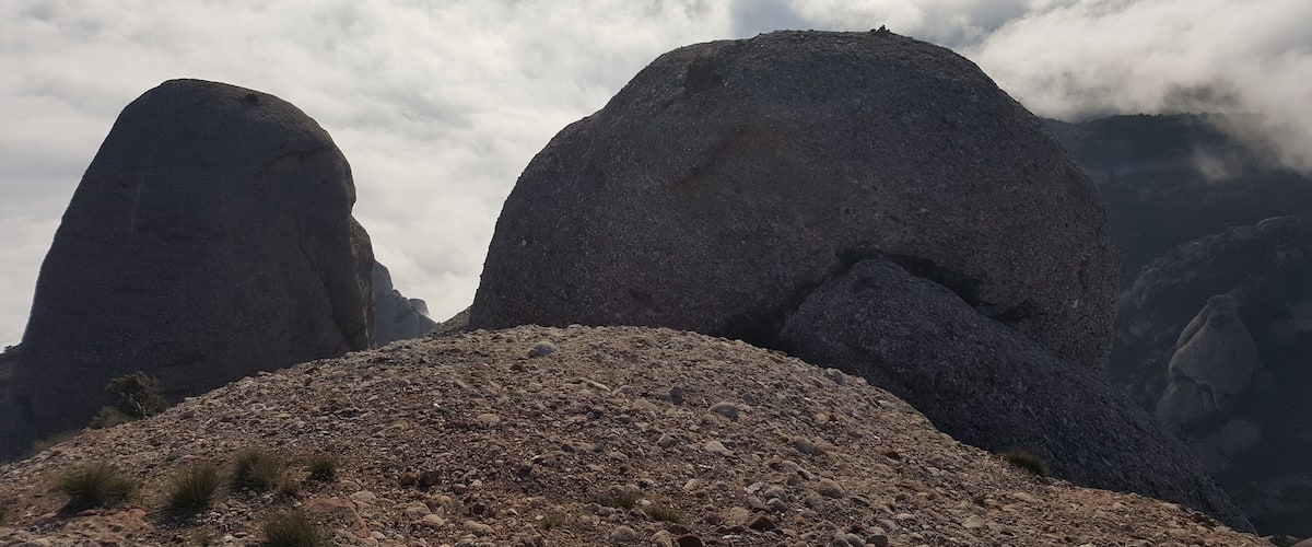 A mountainous landscape with two prominent rock formations and a layer of clouds below.