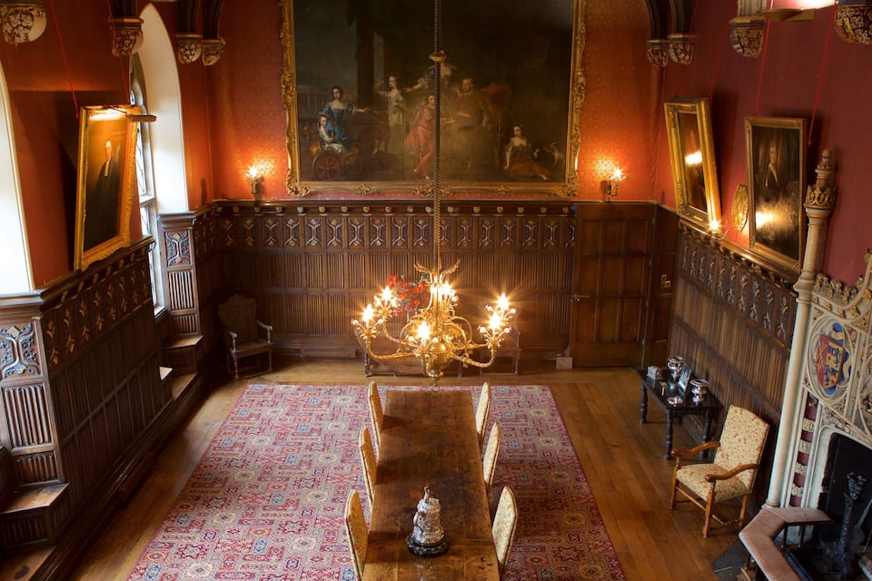 Une vaste pièce agrémentée d’un grand lustre, de boiseries et d’une longue table.