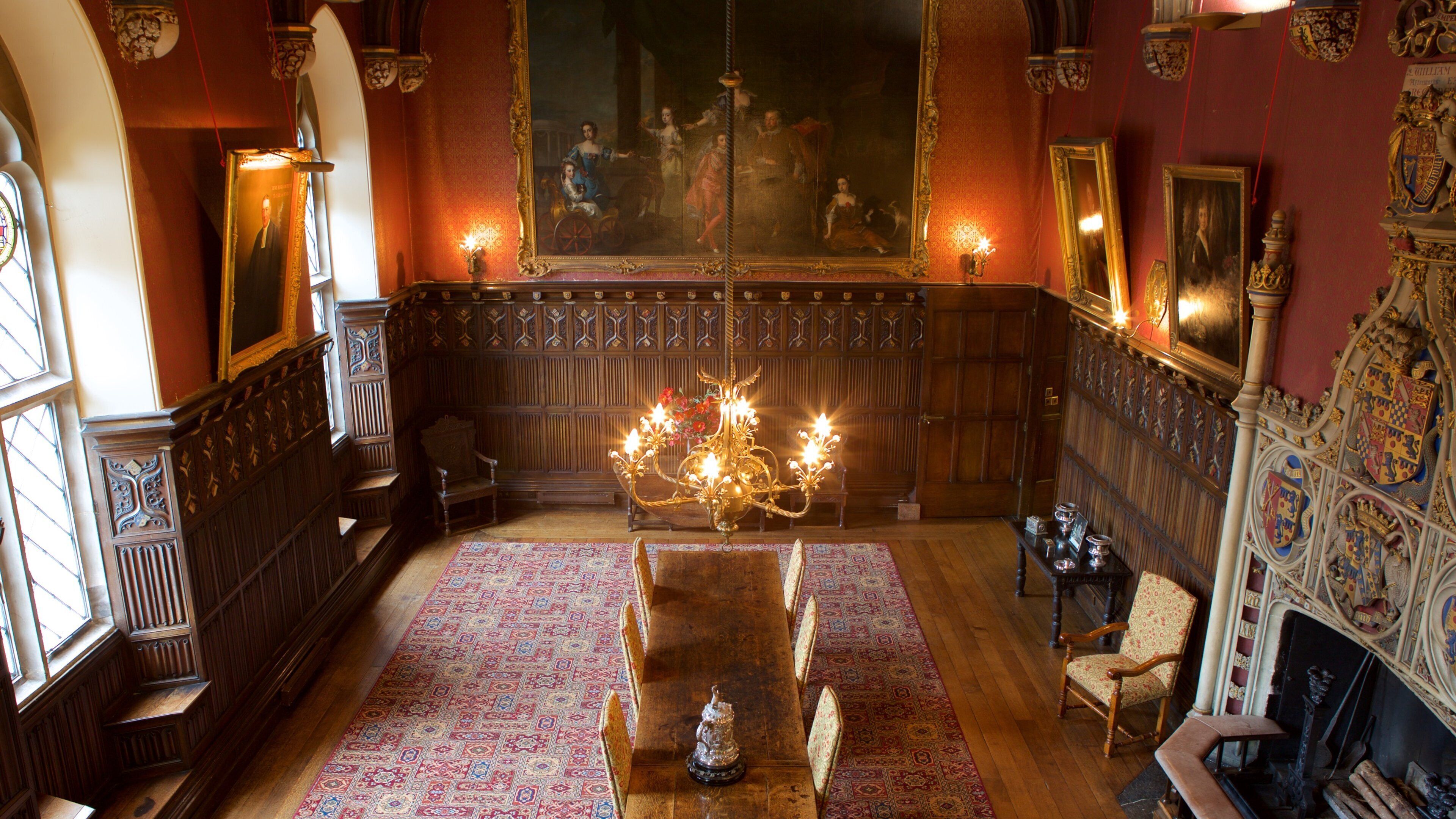 A grand room with a large chandelier, wooden paneling, and a long table.