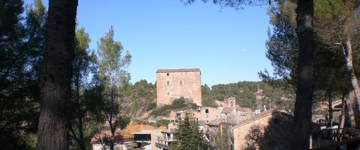 A stone tower on a hill with a forested valley below.