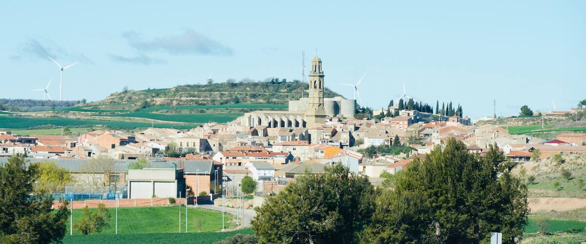 A town with wind turbines, a prominent church, and rolling hills.